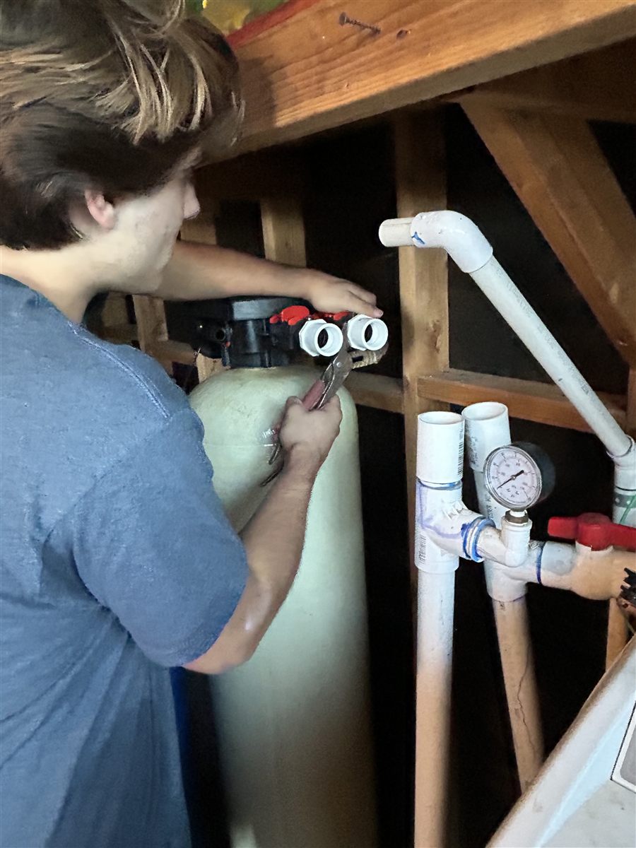 Close-up of a technician connecting a water softener tank