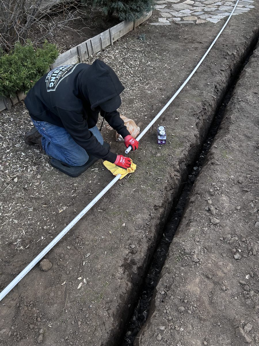 Technician laying PVC pipe in a trench for a new plumbing line